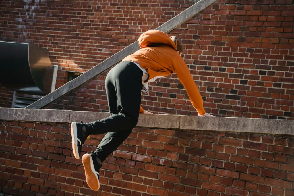 unrecognizable sporty man jumping on brick fence