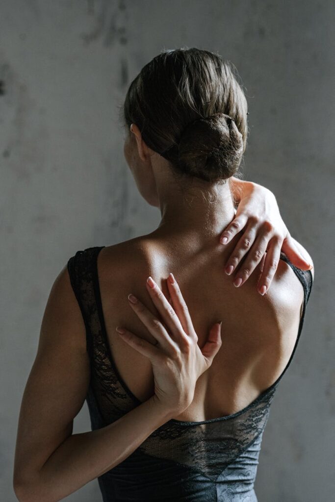 woman in black tank top with hands on her back