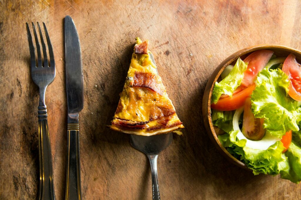 slice of pizza beside fork and knife