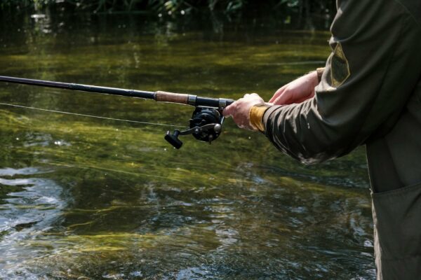 person in brown jacket holding black and silver fishing rod