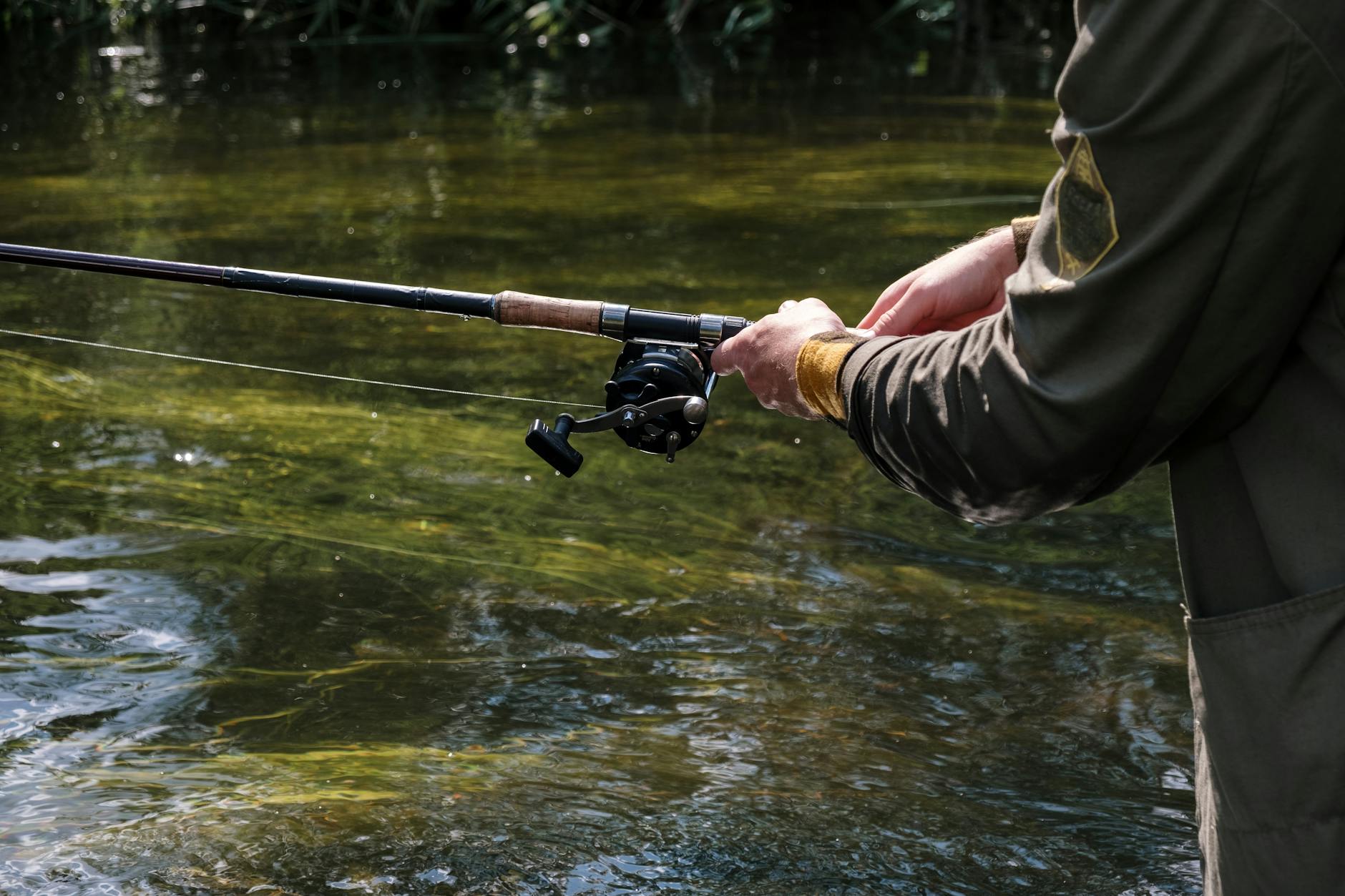 person in brown jacket holding black and silver fishing rod